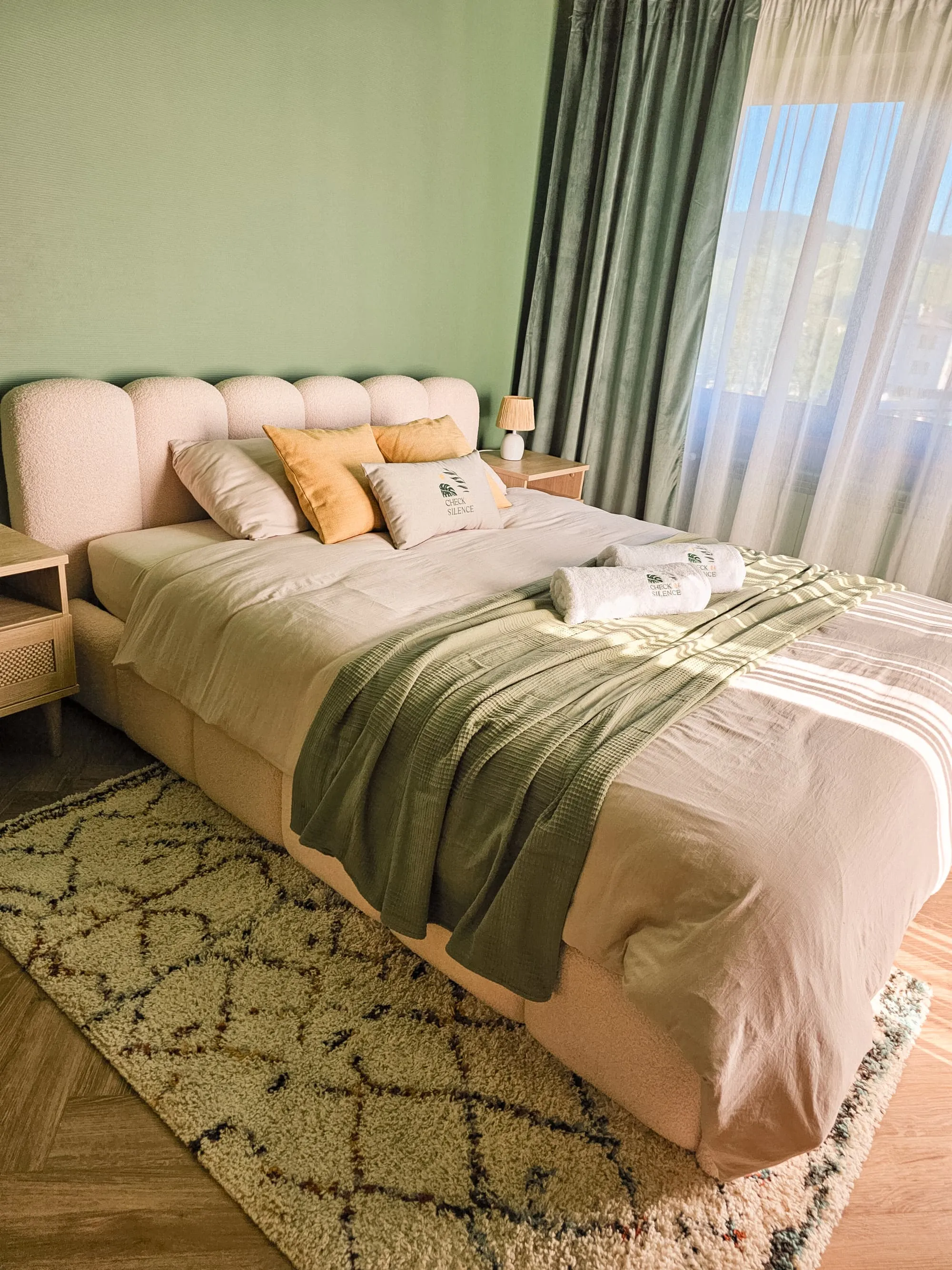 Sypialnia główna Apartamentu Boho z zieloną ścianą i dużym łóżkiem